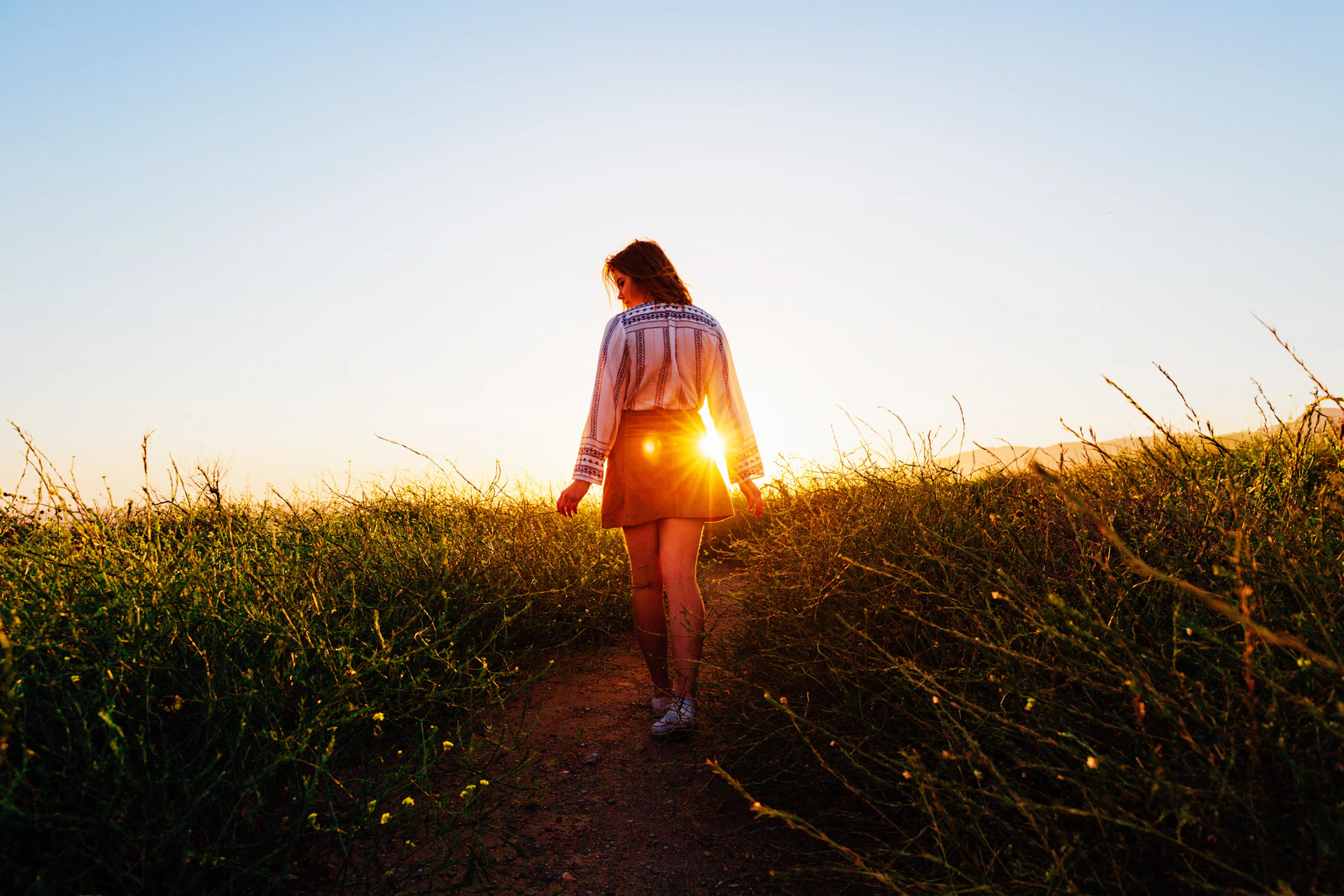 Woman walking along a sunlit path in nature